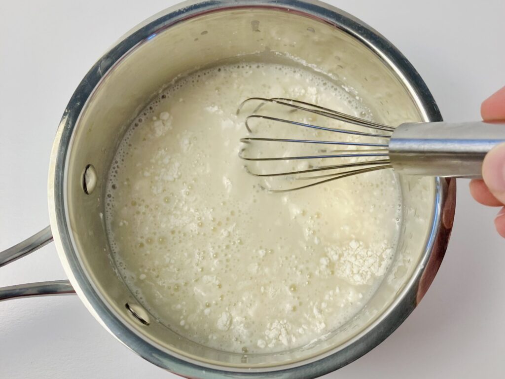 flour and water being whisked in a saucepan to make tangzhong